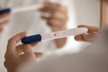 Op de afbeelding is te zien hoe iemand een zwangerschapstest vasthoudt.